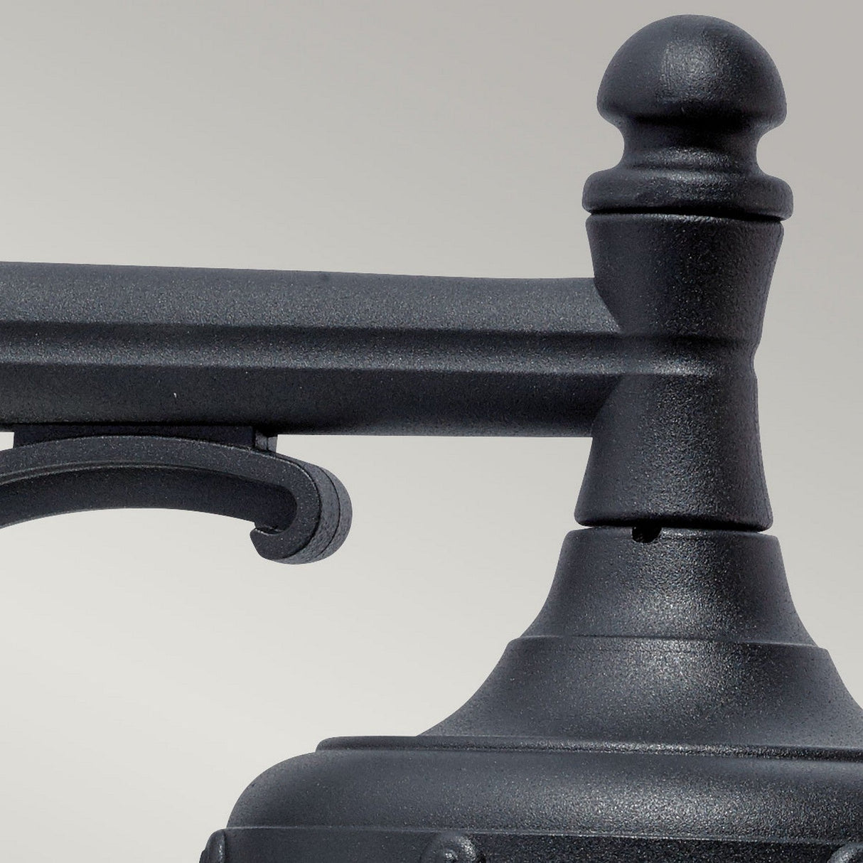 A close-up of the Bologna Outdoor 1 Light Down Wall Light in black showcases its classic design. The image highlights the top portion, featuring the finial and decorative arm, set against a light gray background. With an IP54 rating, it promises durability in diverse weather conditions.