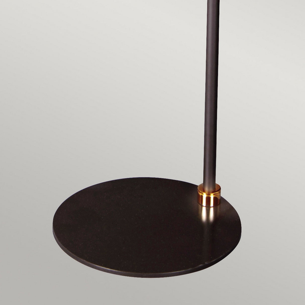 A close-up of the Balance Floor Lamp - Black/Polished Brass features a black circular disk attached to a vertical pole with a polished brass ring at the joint, set against a plain light background—a perfect representation of modern design.