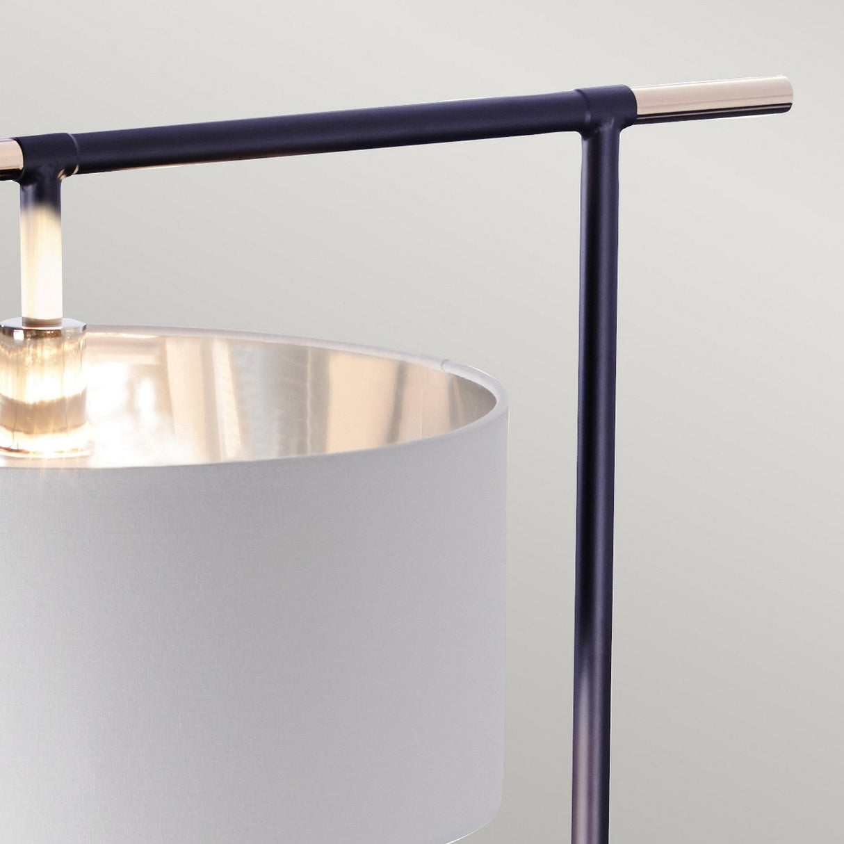 Close-up of the Balance Floor Lamp - Black/Polished Nickel, a striking piece of modern decor with a cylindrical white lampshade and sleek black metal frame. Its minimalist design, featuring a horizontal black bar intersecting the vertical rod, perfects contemporary elegance against a light gray background.