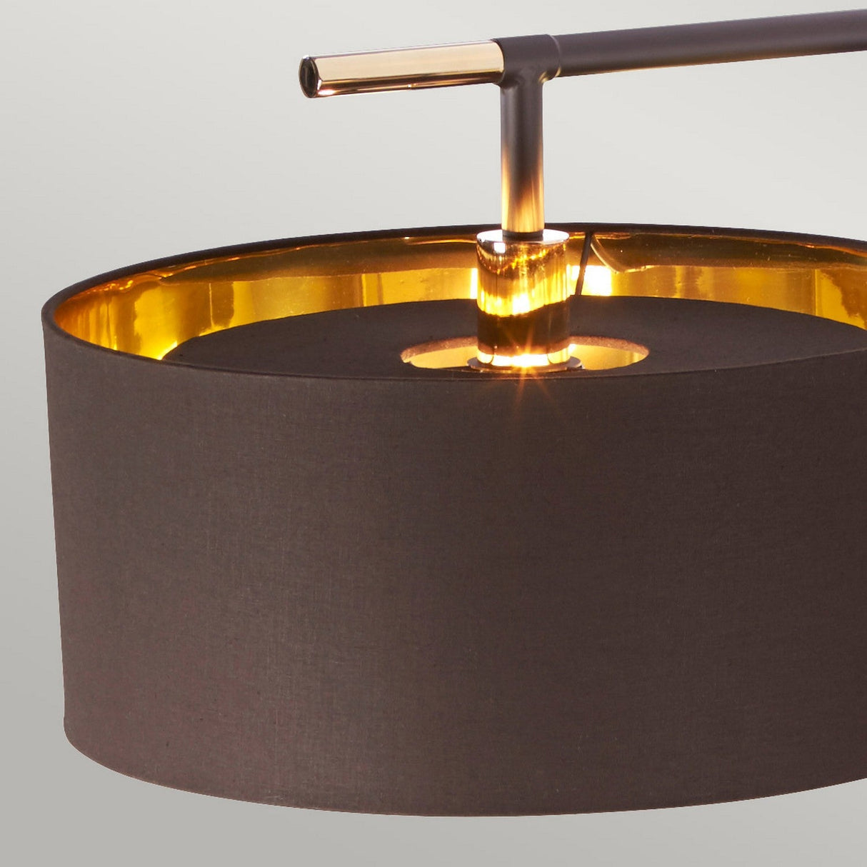 Close-up of the Balance Floor Lamp - Brown/Polished Brass showcasing its cylindrical dark fabric shade and polished brass finish. This lamp emits a warm light from the center, accentuated by its sleek metallic arm, and comes with a fabric diffuser to provide soft illumination against a plain background.