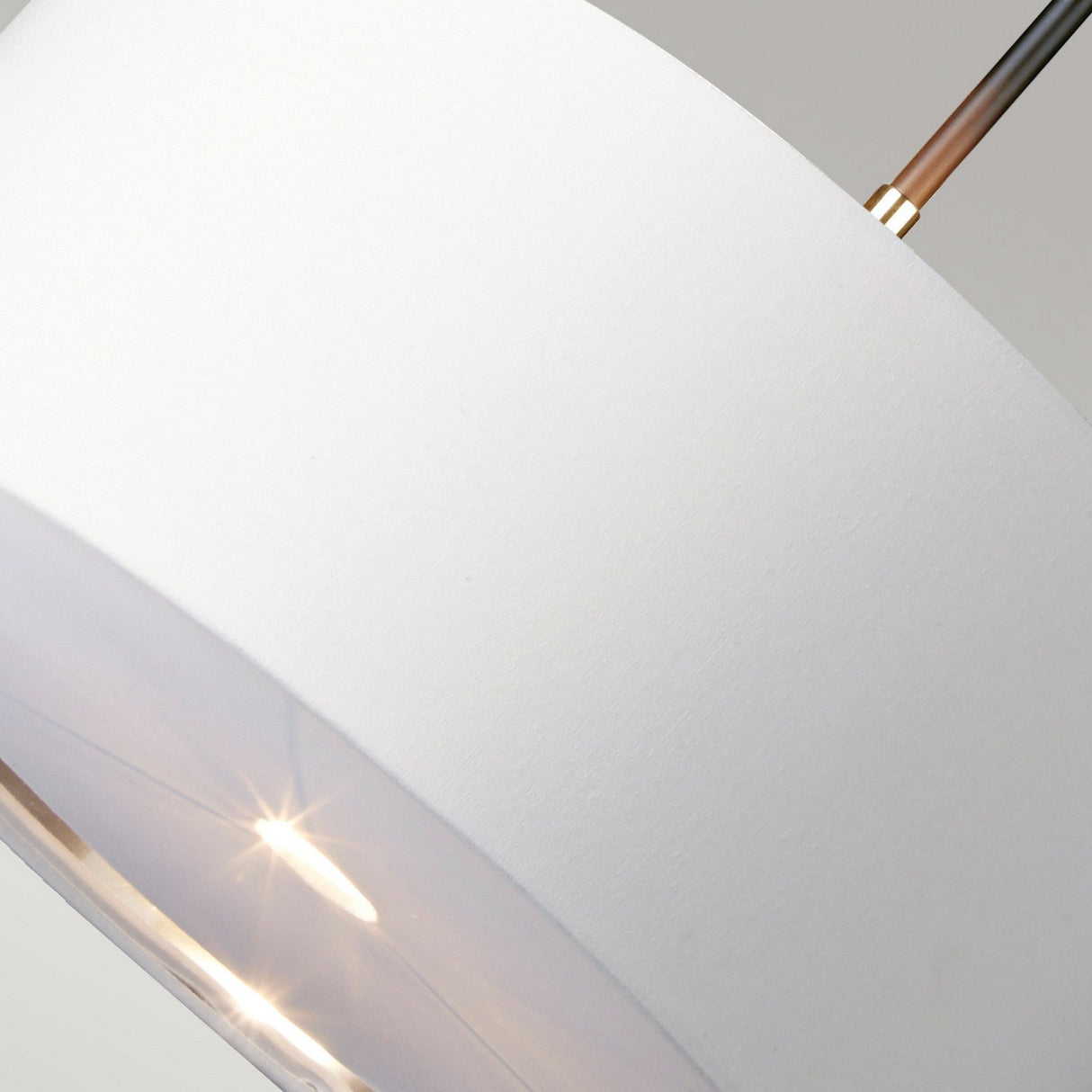 Close-up of a modern white fabric lampshade with a soft glow from an LED lamp inside. The light reflects subtly on the smooth surface and polished nickel, creating a warm and inviting atmosphere. Simple metal supports extend from the top, similar to the elegant design of the Balance Pendant Light - Black/Polished Nickel.