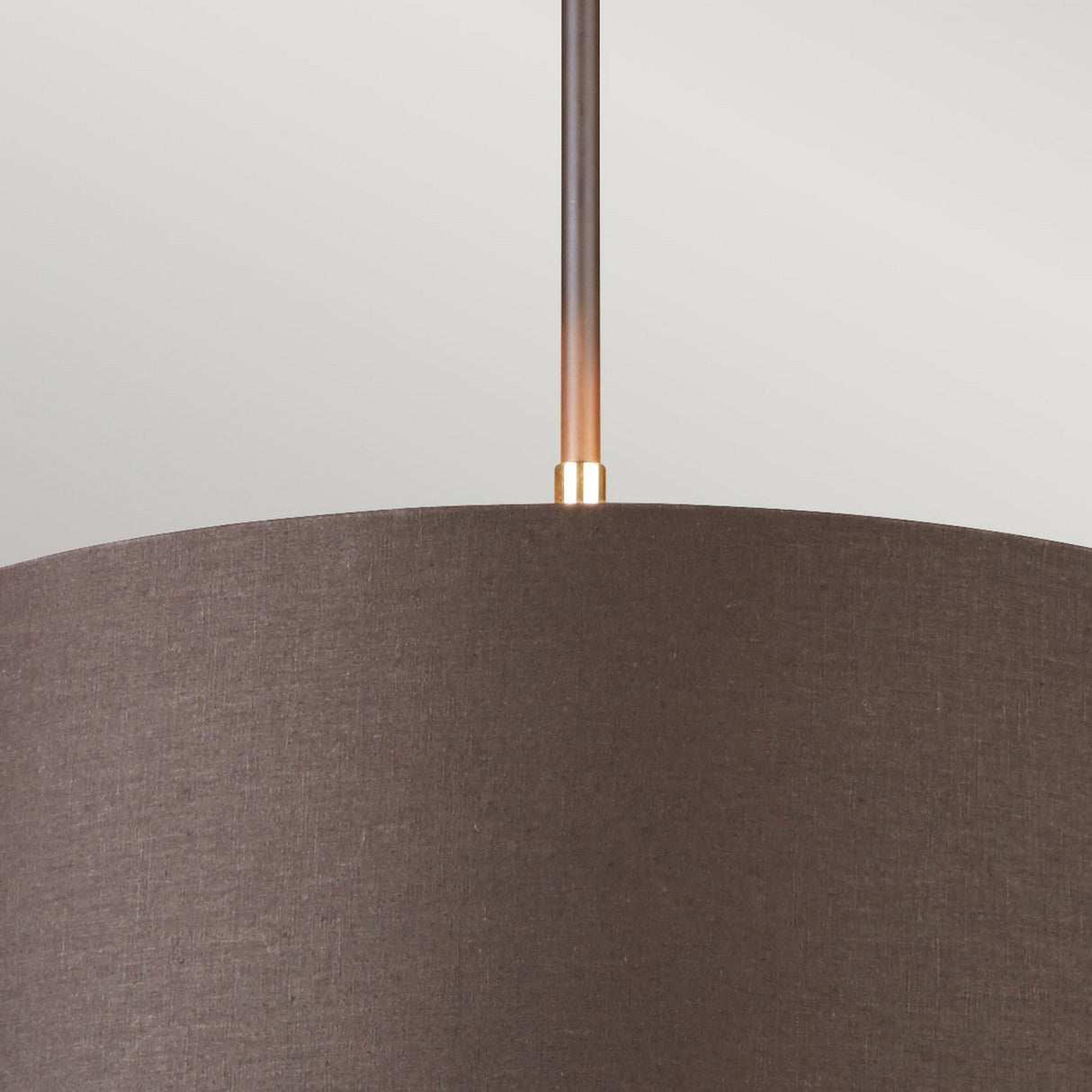 The Balance Pendant Light - Brown/Polished Brass is showcased up close, featuring a brown lampshade and polished brass detailing where the rod connects to the shade. Its modern, minimalist design stands out against a neutral light gray background, highlighting its energy-efficient qualities.