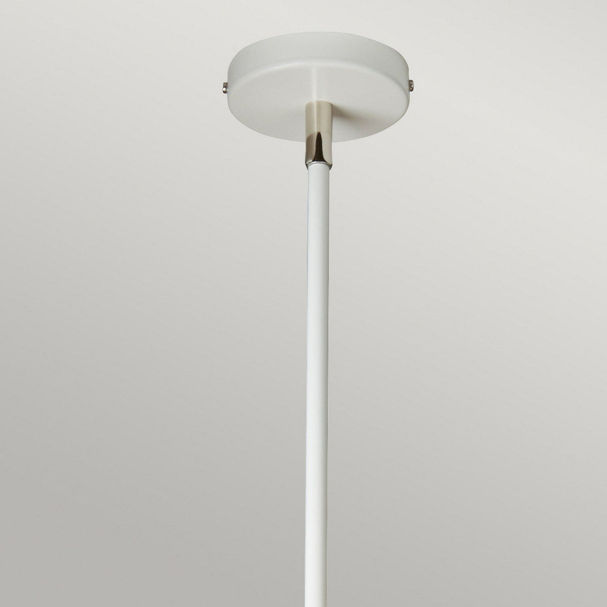 The Balance Pendant Light - White/Polished Nickel is a minimalist fixture that showcases a sleek cylindrical rod extending from a circular ceiling mount. Its uncomplicated design provides modern, energy-efficient illumination against a plain backdrop, making it ideal for contemporary spaces.