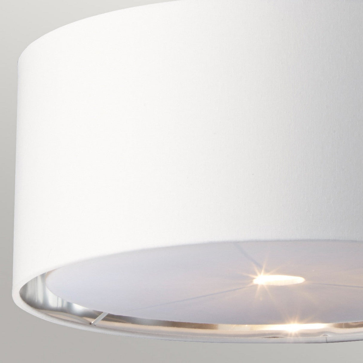 Close-up of a modern, energy-efficient white drum-shaped ceiling light against a gray backdrop. The Balance Pendant Light - White/Polished Nickel is lit, casting a gentle glow.