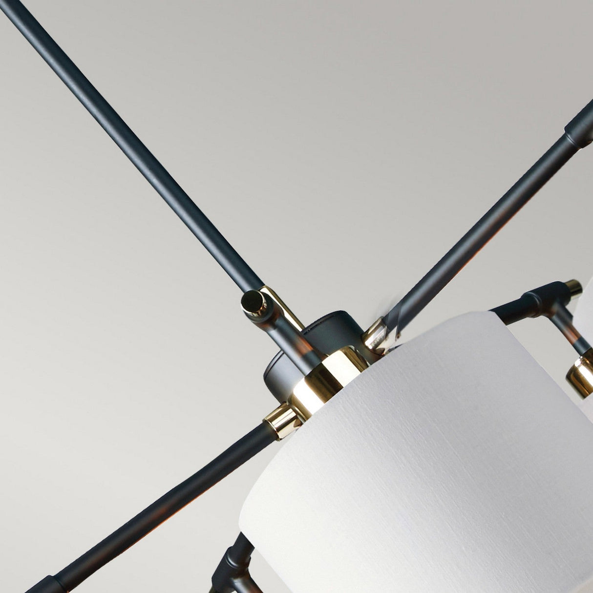 A close-up view of the Balance 5 Light Chandelier showcases its white cylindrical lampshade and polished nickel accents. The design features sleek black metal rods extending in various directions against a light gray background, offering energy-efficient lighting ideal for contemporary spaces.