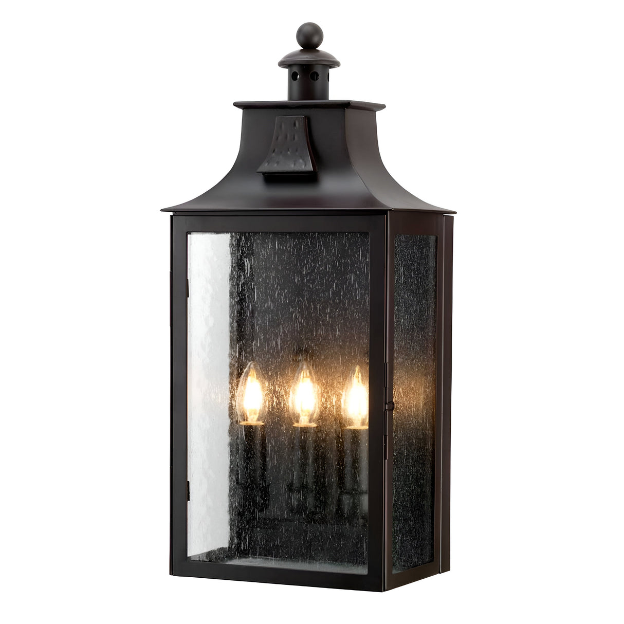 The Balmoral 3 Light Outdoor Wall Lantern - Old Bronze exudes vintage charm with its classic design featuring three candle-style light bulbs. Its glass panes, offering a slightly textured, speckled appearance, enhance the rustic touch. A decorative top and an old bronze finish complete this refined wall-mounted piece.