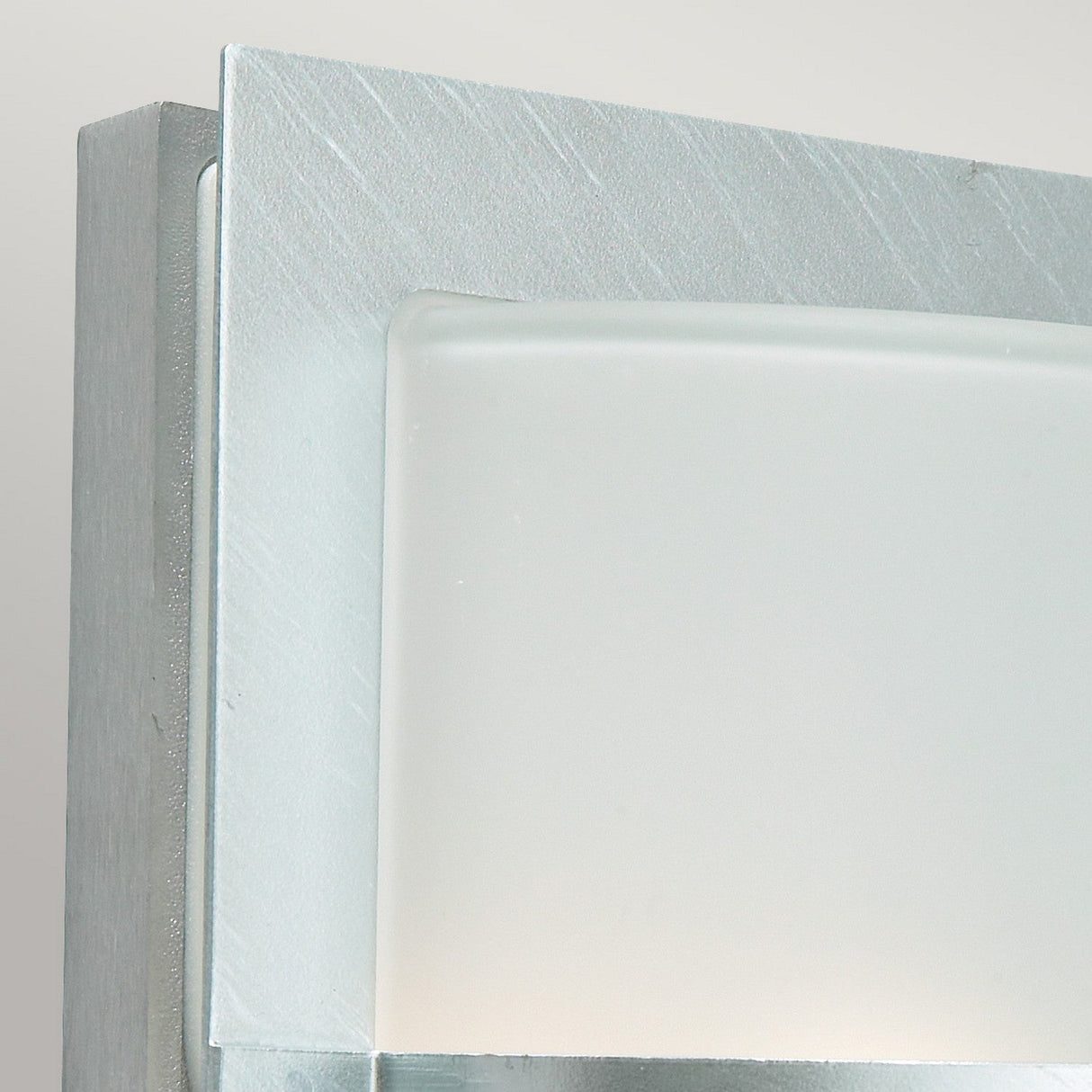 Close-up of the Basel Outdoor 1 Light Wall Lantern in silver, showcasing its minimalist design. This fixture has an IP54 rating and features a frosted glass panel that is partially set within a sleek, metallic rectangular frame against a neutral background.