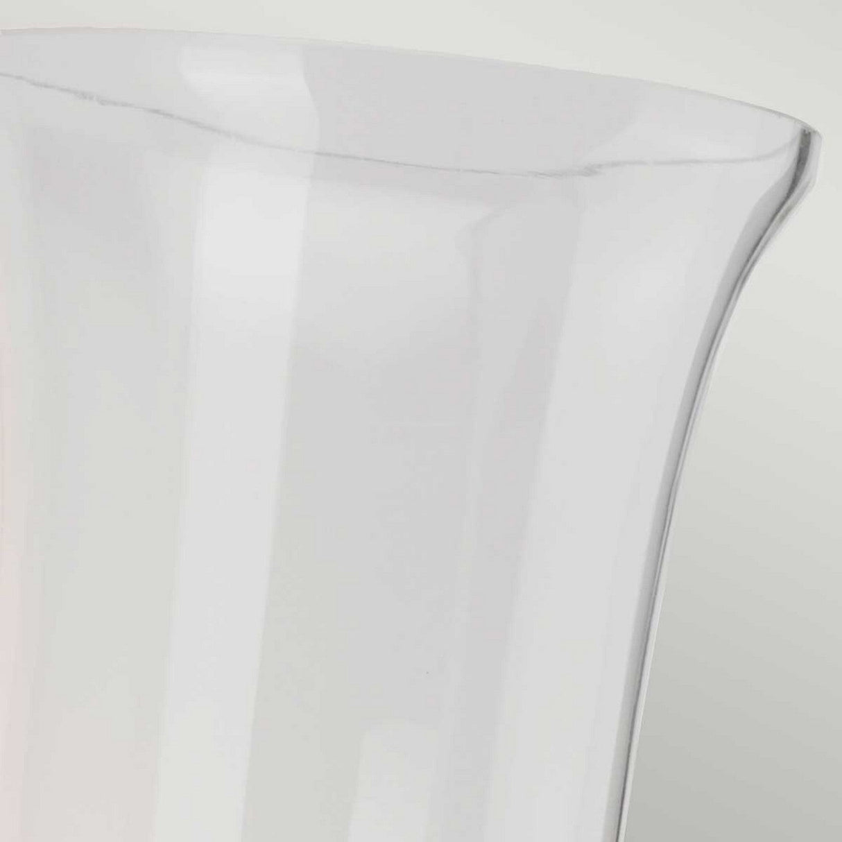 A close-up image showcases the rim of a clear, tall glass vase set against a light gray background, subtly reflecting the sheen of an Austen-2 Wall Light - Polished Chrome. The vase features a smooth, curved edge and appears to be empty.