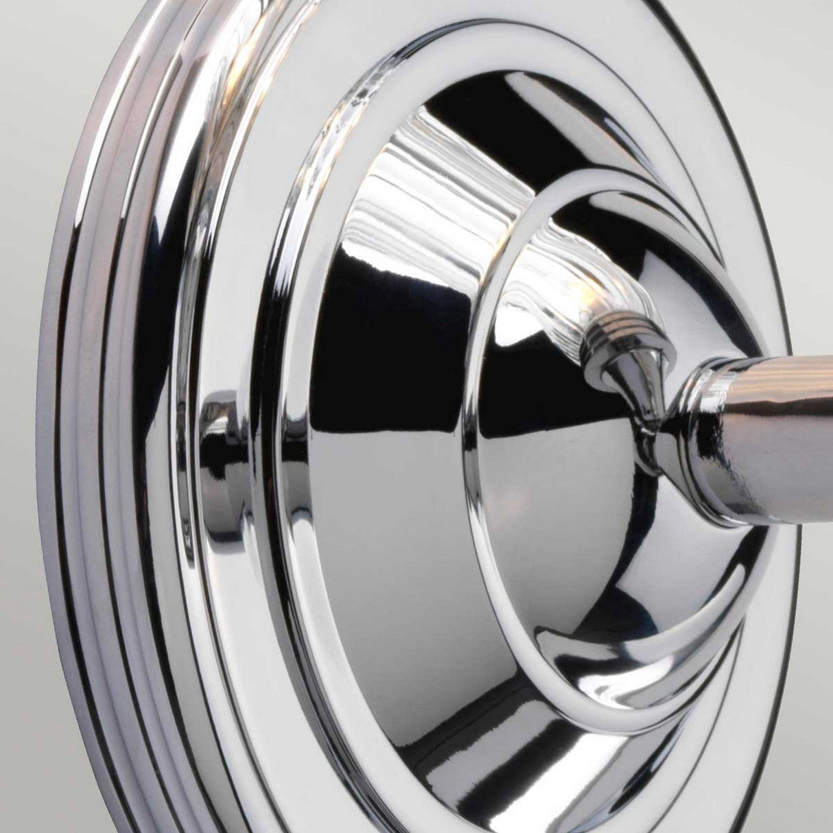 A close-up of the Austen-3 Wall Light in polished chrome reveals its circular design with reflective surfaces, showcasing its seamless integration with energy-efficient LED lighting for an elegant touch.