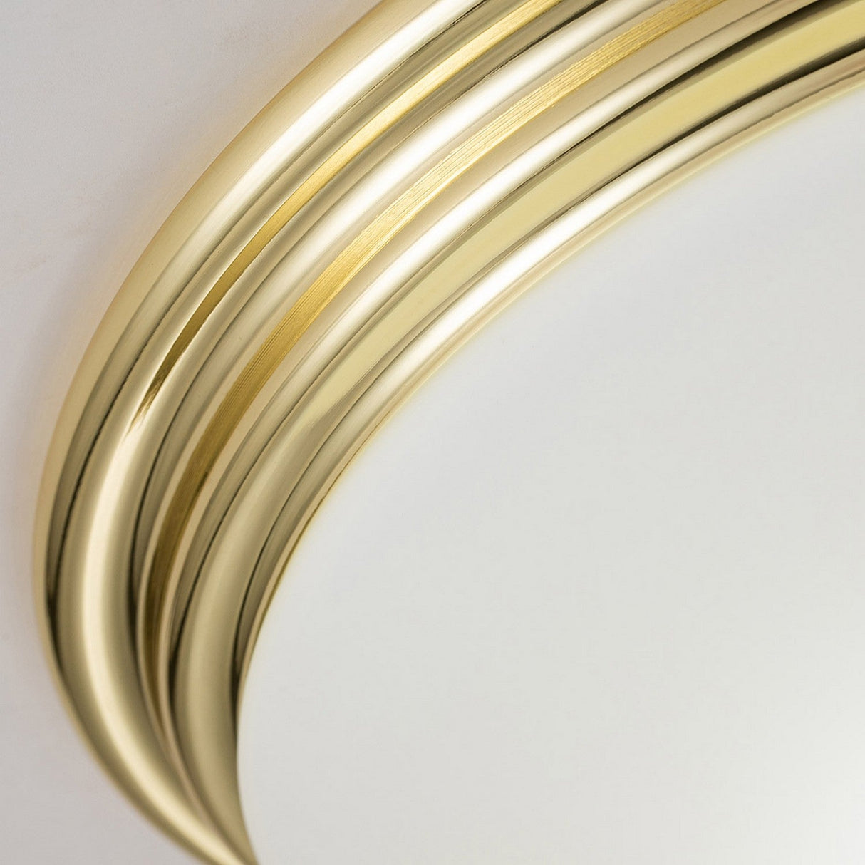Close-up of the Brompton Flush Light - Polished Brass against a light background, resembling an ornate, vintage light fixture, showcasing an elegant design and smooth finish.