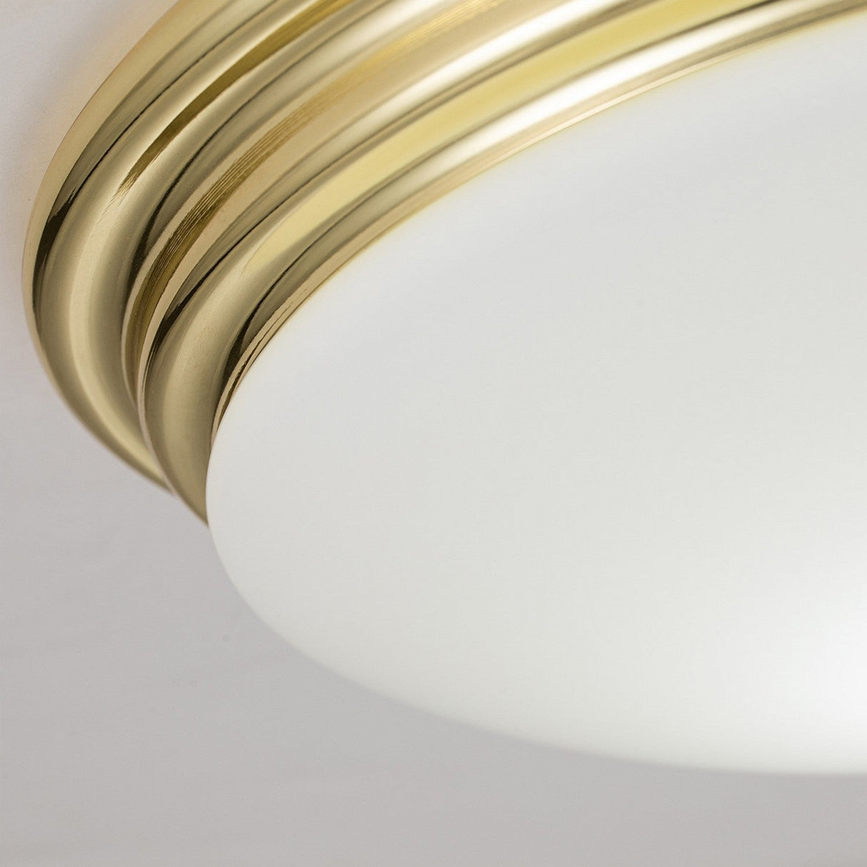 The Brompton Flush Light in polished brass features a close-up of its bathroom ceiling design, highlighted by a frosted glass shade. This fixture blends modern aesthetics with subtle vintage charm, showcasing smooth curves and a seamless finish.