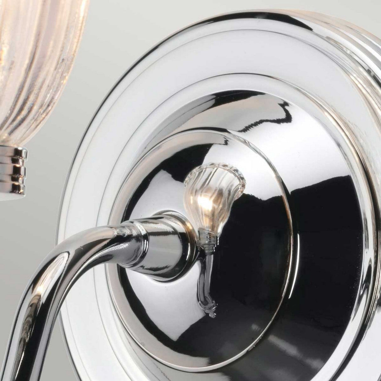 A detailed view of the Carroll-1 Wall Light - Polished Chrome, showcasing its ribbed glass shade. The fixture includes a shiny, circular metal base and an arm that holds an energy-efficient LED bulb, with its polished surface elegantly reflecting subtle patterns.