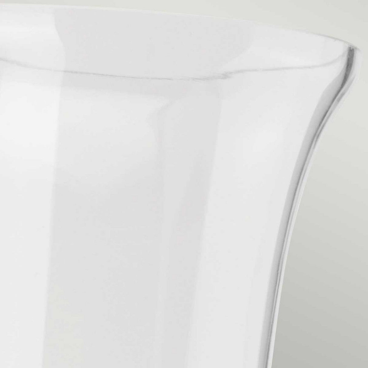 Close-up image of the top portion of a clear glass vase, its smooth, curved rim reminiscent of the Carroll-2 Wall Light in polished chrome, set against a soft gray background.