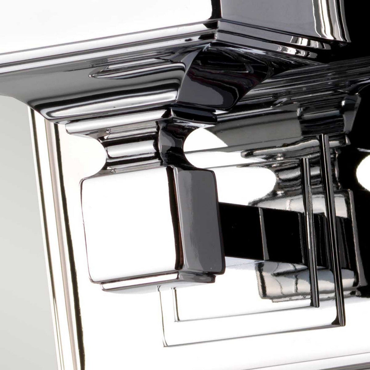 Close-up of the Cambridge Wall Light in polished chrome features overlapping rectangular elements that reflect light, creating an abstract, modern look similar to an opal glass shade.