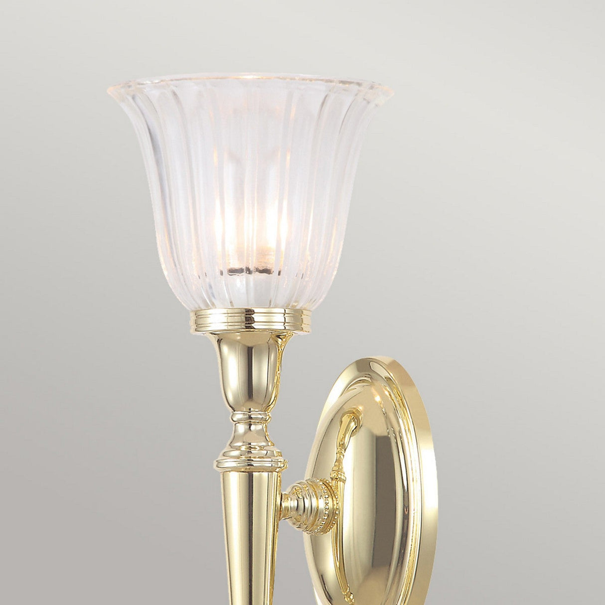 The Dryden-1 Wall Light in Polished Brass boasts an elegant design with a fluted glass shade that emits a soft light, crafting a sophisticated ambiance. Its polished brass surface subtly reflects light, enhancing its classic and refined look, while being compatible with an LED G9 lamp for efficient illumination.