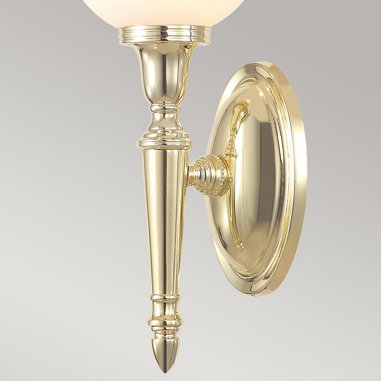 The Dryden-3 Wall Light in polished brass showcases an elegant, tapering design with a round backplate. It features a classic style and includes a single upward-facing LED G9 lamp with an opaque bulb.