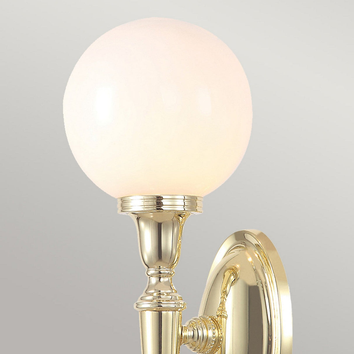The Dryden-3 Wall Light in polished brass showcases an ornate design, complemented by a round, frosted glass globe that emits a soft, warm glow. Inside, the LED G9 lamp ensures energy-efficient illumination, while the sconce is elegantly mounted on an oval brass wall plate.