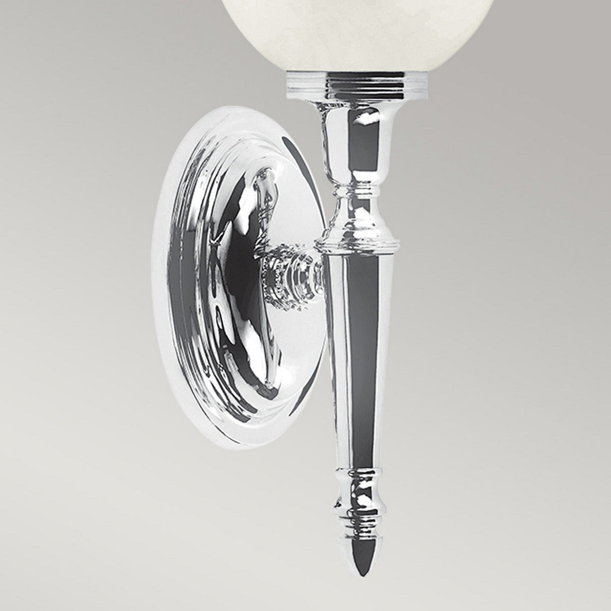 Introducing the Dryden-3 Wall Light in polished chrome, this fixture boasts an oval backplate and a sleek, pointed arm that beautifully supports a frosted white glass shade. Enhanced with an LED G9 lamp, its design exudes elegance and reflects sophistication.