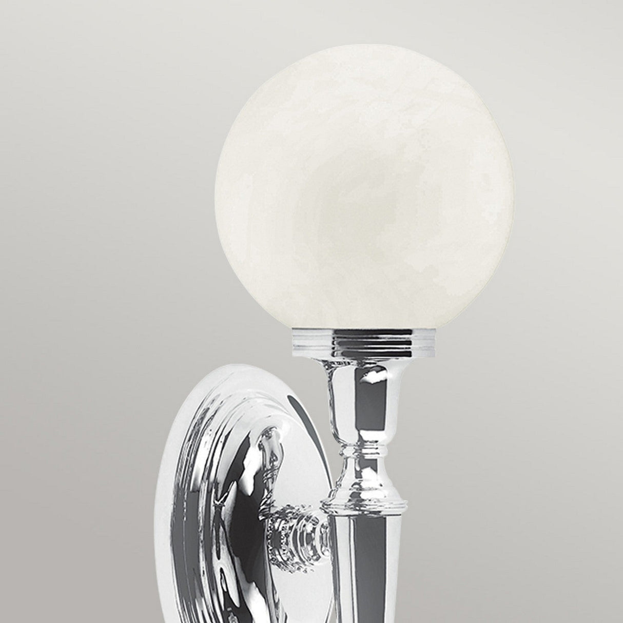 Introducing the Dryden-3 Wall Light in polished chrome, showcasing a round, frosted glass shade against a light gray background. This fixture embodies a modern and sleek design, ideal for use with an LED G9 lamp to ensure efficient illumination.