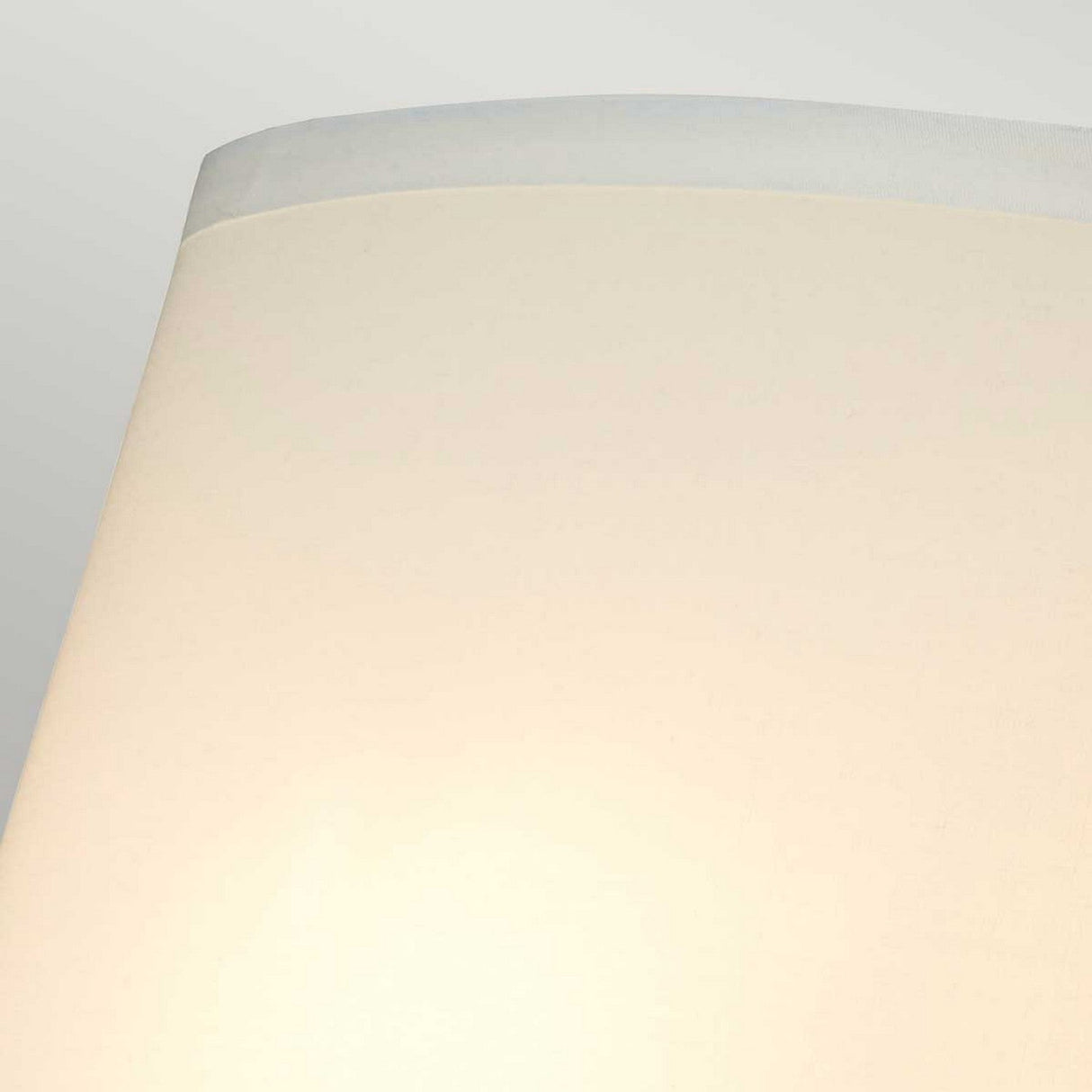 Close-up of a simple cream-colored lampshade against a light gray background, reminiscent of the sleek design found in the Falmouth Wall Light - Gold/White Shade. The shade features a smooth, cylindrical shape with a slightly darker rim at the top, adding elegance similar to its gold finish.