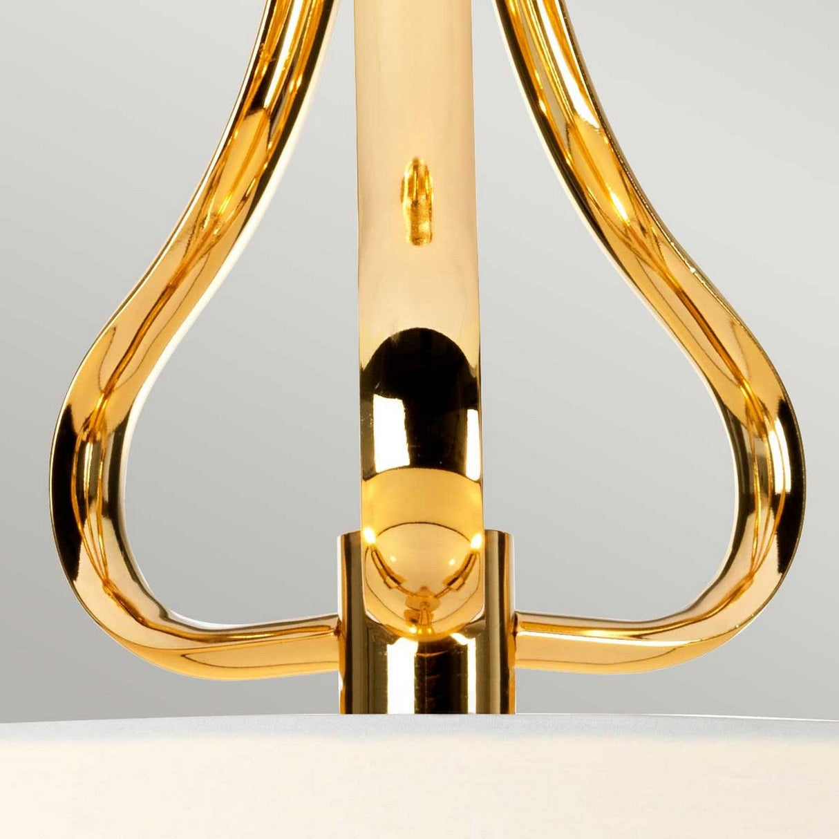 A close-up of the Falmouth 3 Light Semi Flush fixture reveals its striking French Gold-colored metal structure with graceful curves, reminiscent of a refined semi-flush design. The polished surface brilliantly reflects light, set against a light background and subtly hinting at the sophisticated LED lighting technology housed within.