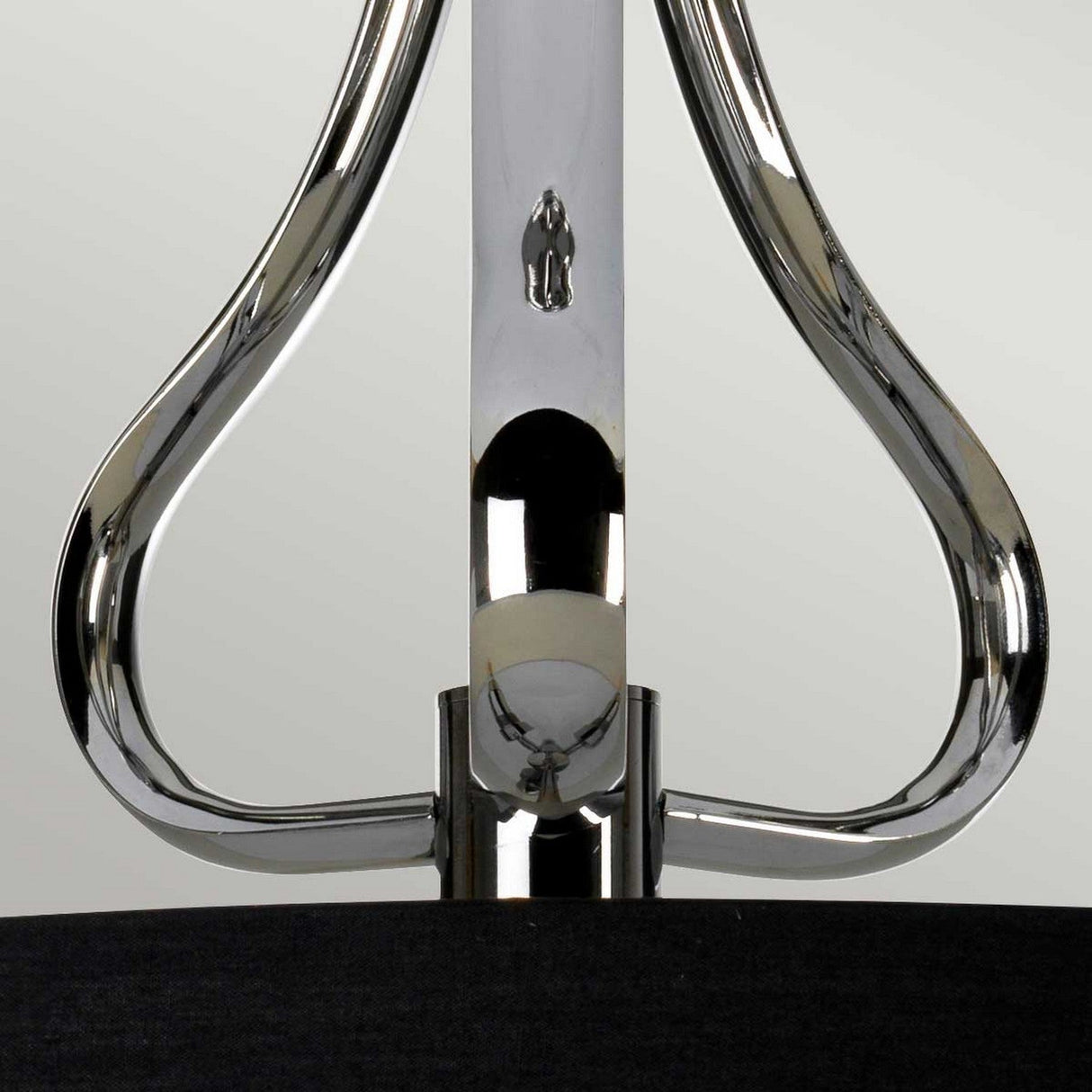 A close-up of the Falmouth 3 Light Semi Flush in polished chrome and black shade reveals a metallic, symmetrical design with reflective surfaces. Against a simple backdrop, its shiny curved elements converge at a central point, embodying an abstract and modern style reminiscent of integrated LED technology.