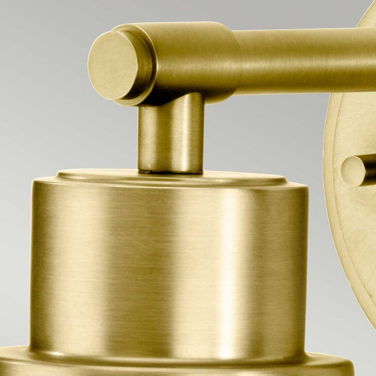 Close-up of the Morvah 1 Light Outdoor Wall Light showcasing its cylindrical base and horizontal arm. This vintage-inspired fixture features a brushed brass finish, elegantly contrasted against a soft gradient of gray tones.