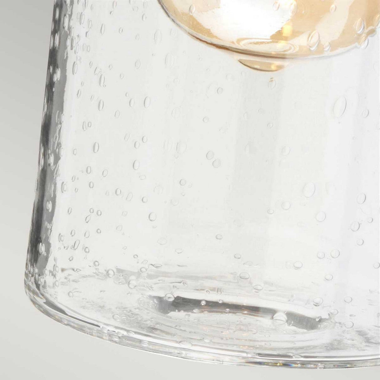 Close-up of the Morvah 1 Light Outdoor Wall Light in white, featuring a clear glass lampshade with bubbles and a softly glowing LED Edison bulb inside. The transparency and texture of the glass provide an elegant and modern design, ideal for enhancing any space.