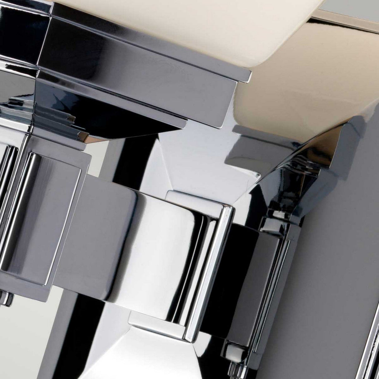 A close-up of the polished chrome Shirebrook 1 Light Wall Light showcases its sharp angles and reflective surfaces. The sleek design aligns perfectly with the bathroom's contemporary faucet, enhancing the modern aesthetic. This impeccably styled fixture meets IP44 rated standards for safety and elegance in wet areas.