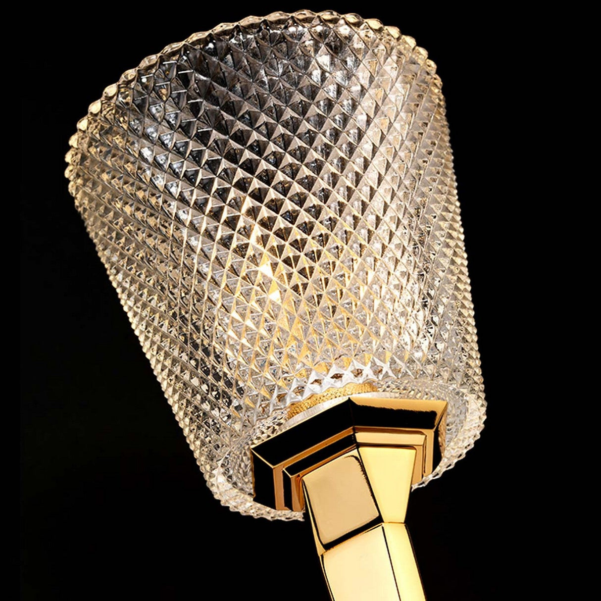 Close-up of the Verity 1 Light Wall Light in polished gold, showcasing its elegant crystal design with a geometric, faceted pattern. This luxurious wall light features an energy-saving LED lamp that illuminates the intricate crystals, casting a warm, opulent glow against the dark background.