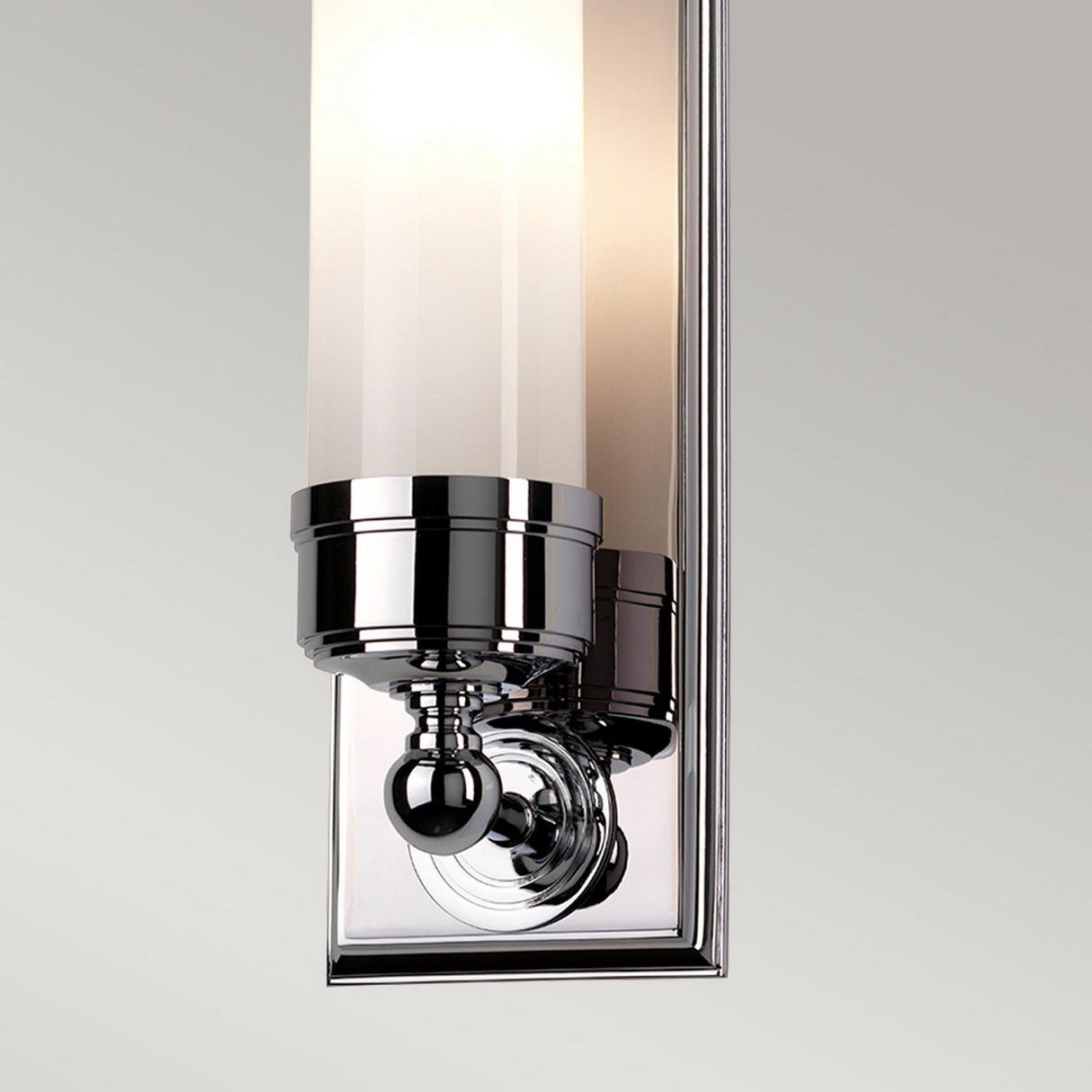 Close-up of the Worcester 1 Light Wall Light, showcasing its transitional design with a polished chrome finish and a cylindrical frosted glass shade, set against a plain light gray background.