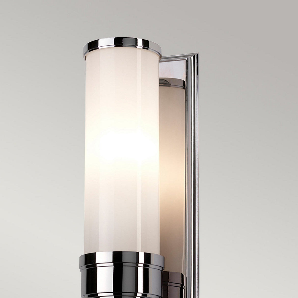 The Worcester 1 Light Wall Light in polished chrome boasts a sleek metallic finish and a cylindrical frosted glass shade. Its polished chrome coating emits a warm glow that enhances the transitional design, with the fixture elegantly mounted on a rectangular metal plate.