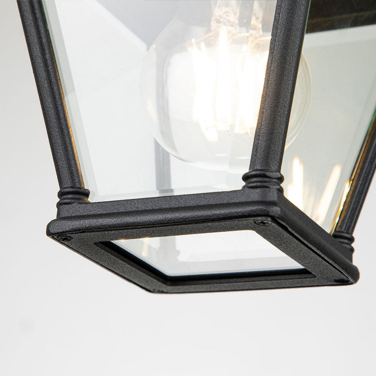 Close-up of the Bayview 1 Light Outdoor Porch Ceiling Light in black, showcasing its angular design and clear glass panels with a visible bulb inside. Its modern, classic look makes it perfect for outdoor lighting.