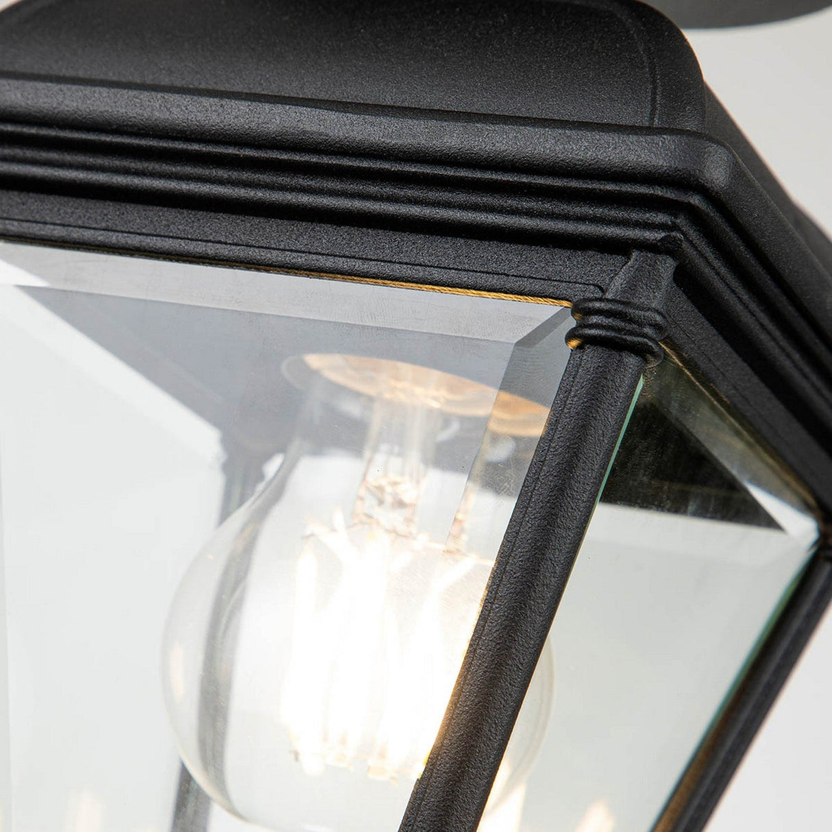 Detailed view of the Bayview 1 Light Outdoor Porch Ceiling Light in black, featuring an aluminium frame and glass enclosure with a clear incandescent bulb inside. The bright illumination highlights its sleek design and clean lines, making it an ideal choice for a porch ceiling light.