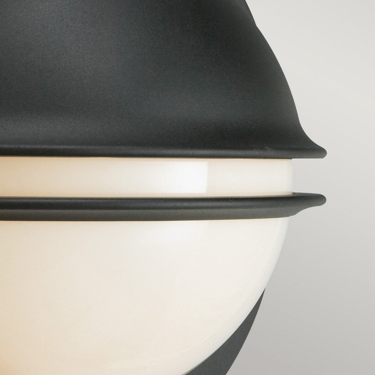 Close-up of the Berlin Outdoor 1 Light Wall Light in matte black, featuring a modern round design with frosted white glass. The fixture's sleek, layered detailing stands out against a neutral background.