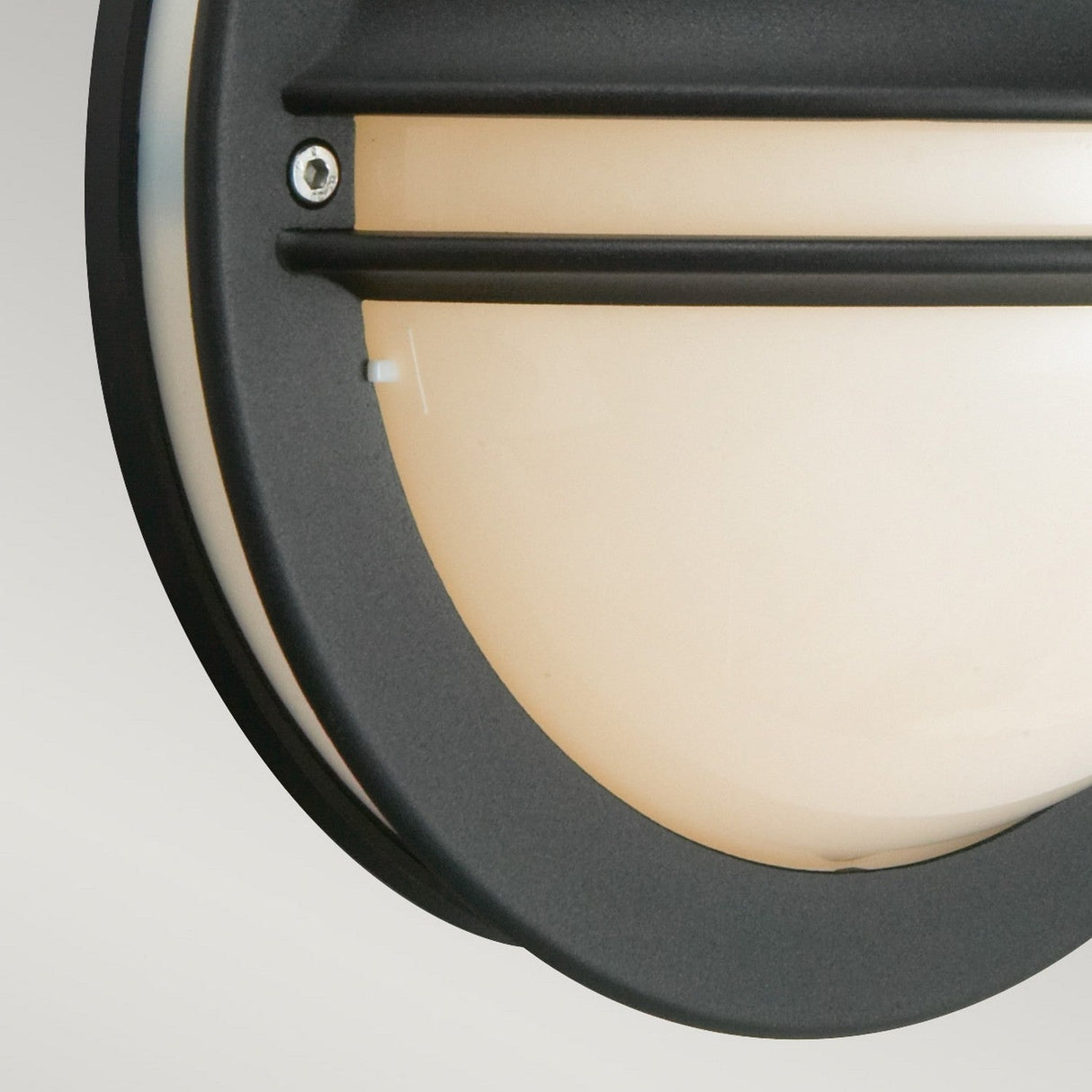 Close-up of the Berlin Outdoor 1 Light Wall Light in black, featuring a round design with an eyelid bulkhead style. It includes a frosted opal shade adorned with horizontal black bars and a visible screw that secures the frame. Perfect for stylish illumination and long-lasting durability, it has an IP54 rating for dust and water resistance.