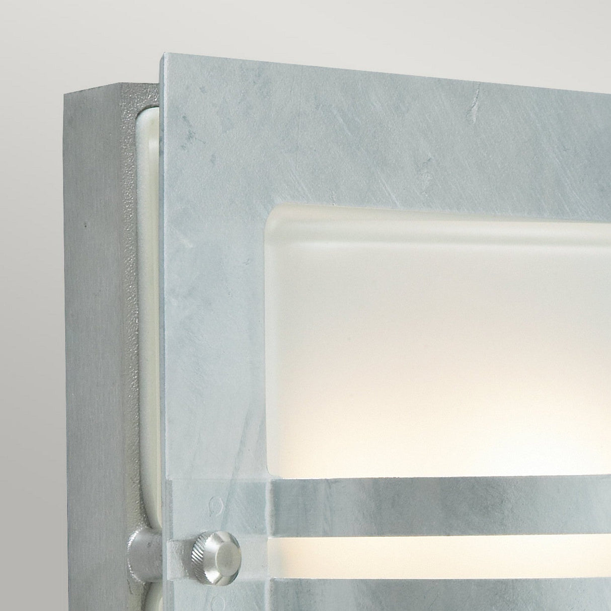 Close-up of the Bern Outdoor 1 Light Wall Lantern, featuring an Art Deco-inspired design with a frosted rectangular glass cover. This wall fixture showcases a sleek silver finish and emits a gentle, diffused light, ideal for enhancing your outdoor decor.