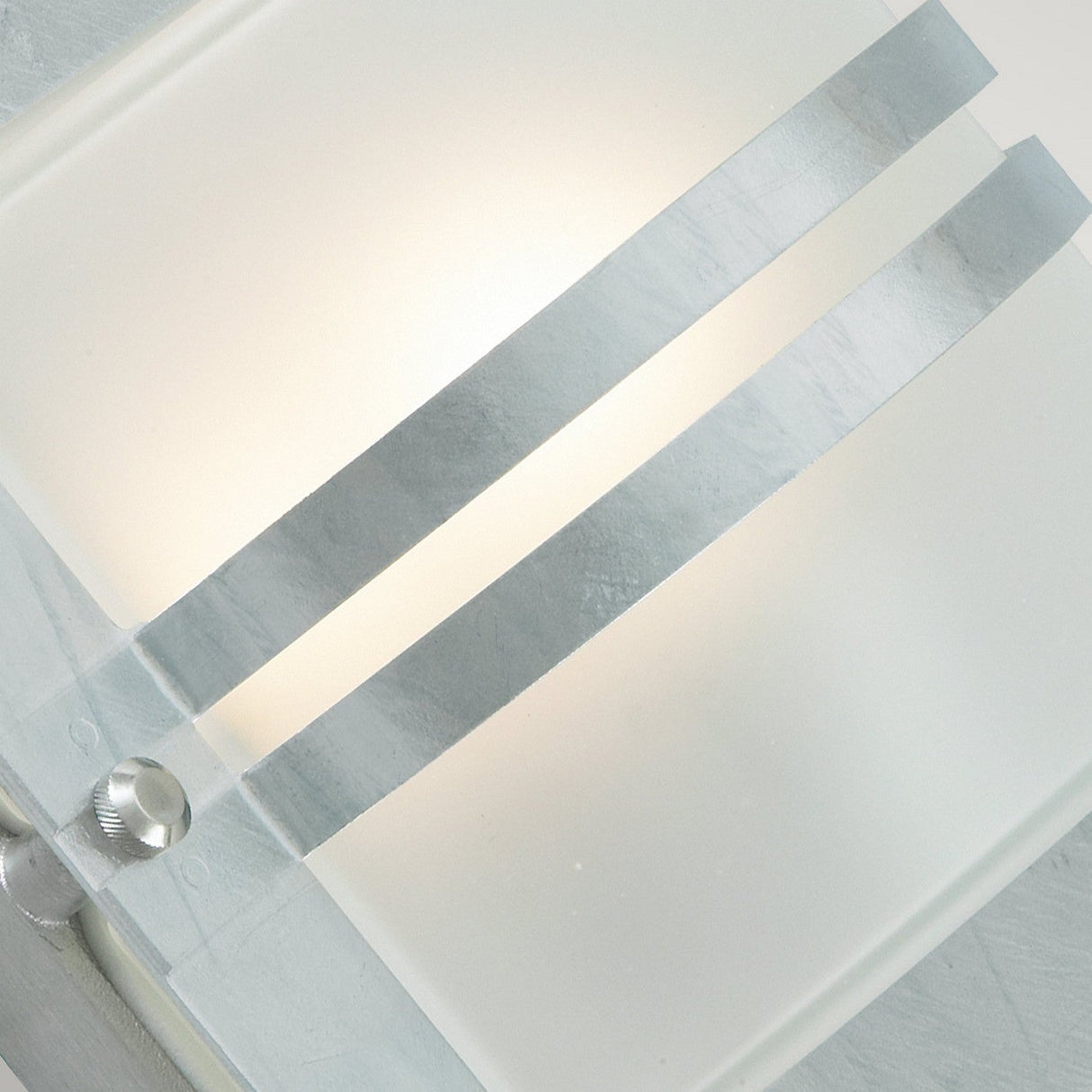 A close-up of the Bern Outdoor 1 Light Wall Lantern in silver, featuring frosted glass and two metallic horizontal bands. This lantern emits a soft glow, delivering a minimalist yet sophisticated aesthetic that is ideal for elevating your outdoor decor.