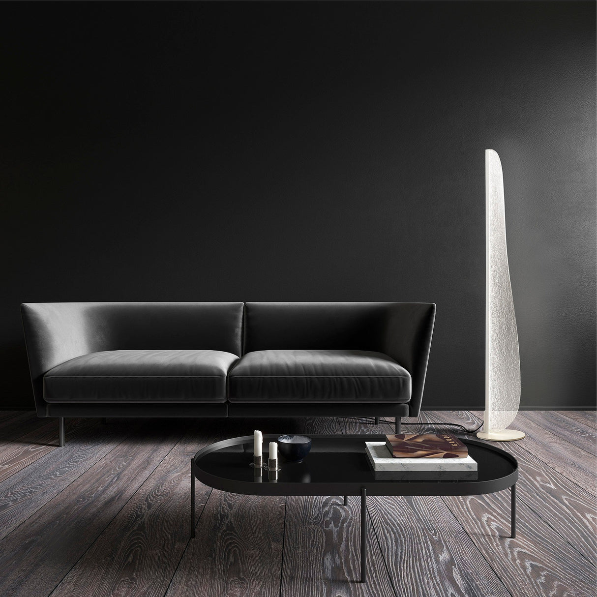 A modern living room features a black leather sofa, a sleek round coffee table with books and decor, the Bianca Small LED Floor Lamp 20W 3000K - White as an accent, dark wood floors, and a plain black wall.