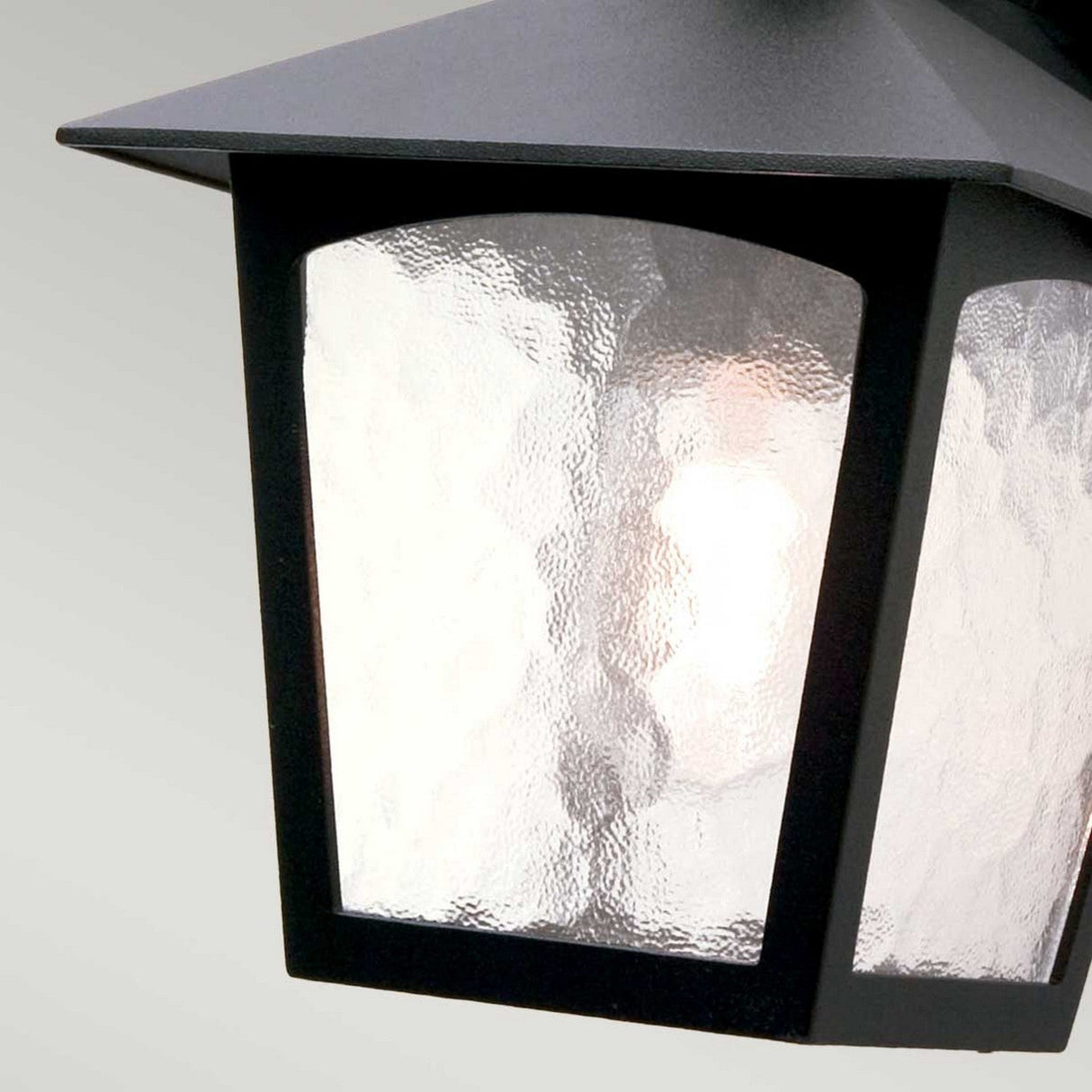 Close-up of a York 1 Light Outdoor Wall Down Light in black, featuring frosted glass panels that reveal the light bulb inside against a plain gray background—perfect for enhancing any garden wall light setting.