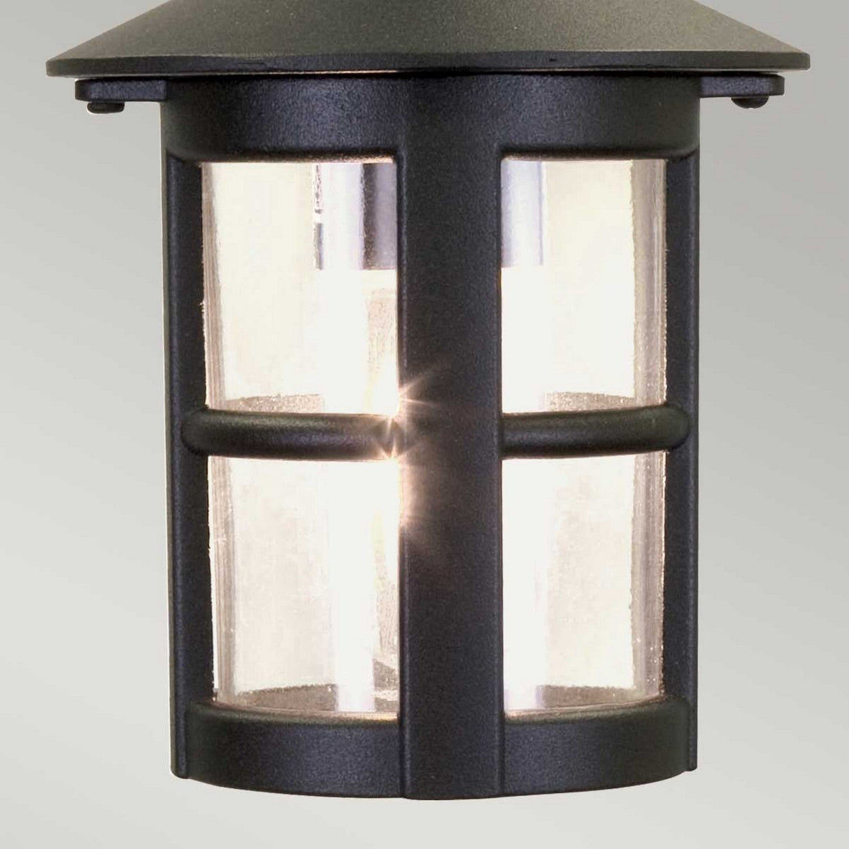 The Hereford 1 Light Outdoor Chain Pendant in Black features a classic lantern shape with a dark metal frame and distinctive vertical and horizontal bars. Perfect for upgrading your outdoor lighting, it emits a warm glow through its clear glass panels, beautifully illuminating the pendant.