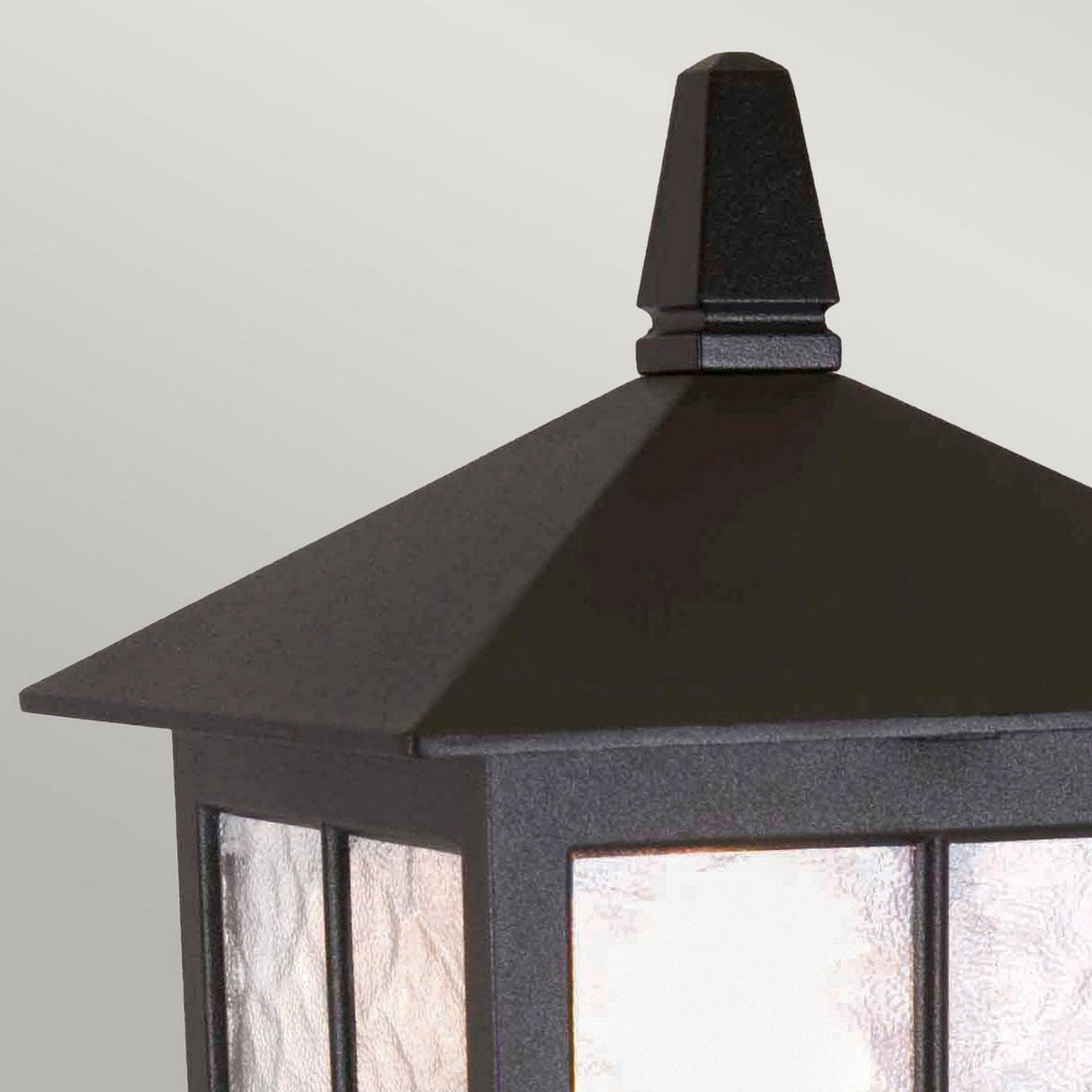 A close-up of the Winchester 1 Light Pedestal Light - Black, an outdoor lantern featuring a peaked top and frosted glass panel. Made from die-cast aluminum, this fixture exudes vintage charm against a neutral background.