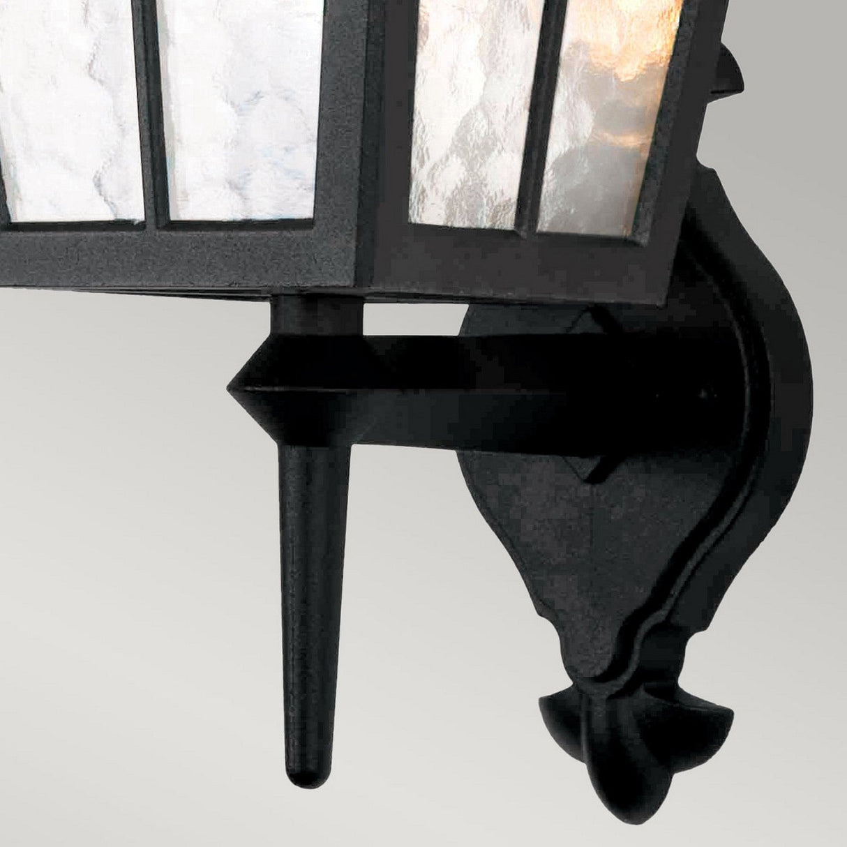 The Canterbury Outdoor Wall Lantern Up - Black is a detailed view of an intricate, black lantern crafted from die-cast aluminium. It features frosted glass panels and an angular support bracket, all showcasing a traditional design against a simple background.