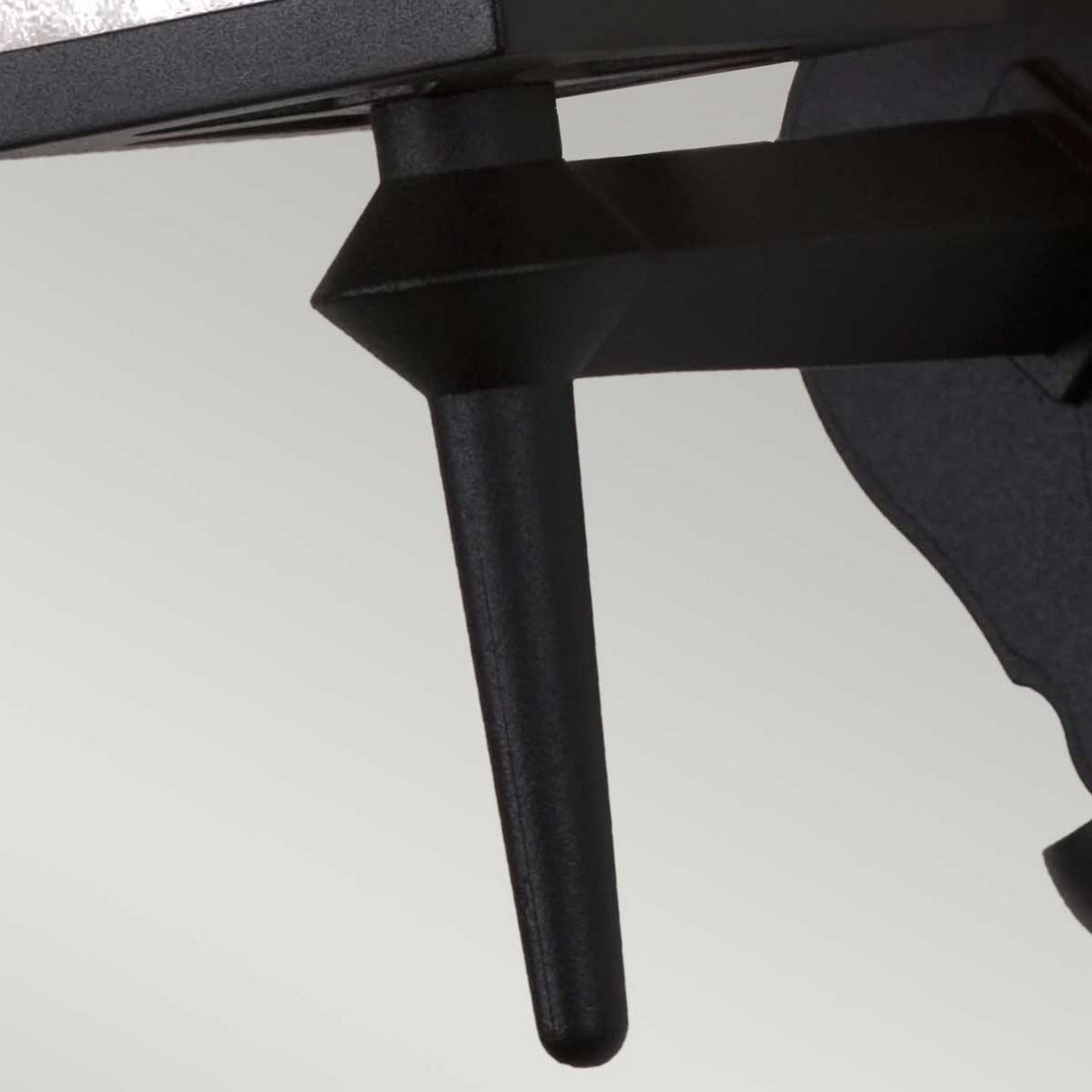 Close-up of the York 1 Light Outdoor Wall Up Light in black, featuring a triangular-shaped metal design connected to a flat, textured surface. This weather-resistant fixture is set against a plain off-white background.