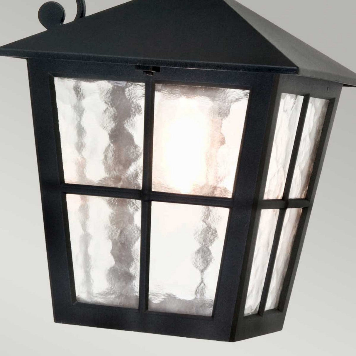 The Canterbury Outdoor Wall Lantern Down in Black boasts a black metal frame with four textured glass panels, providing a warm, diffused glow. Made from durable die-cast aluminum, it's designed to withstand the elements while adding a timeless charm to your exterior.