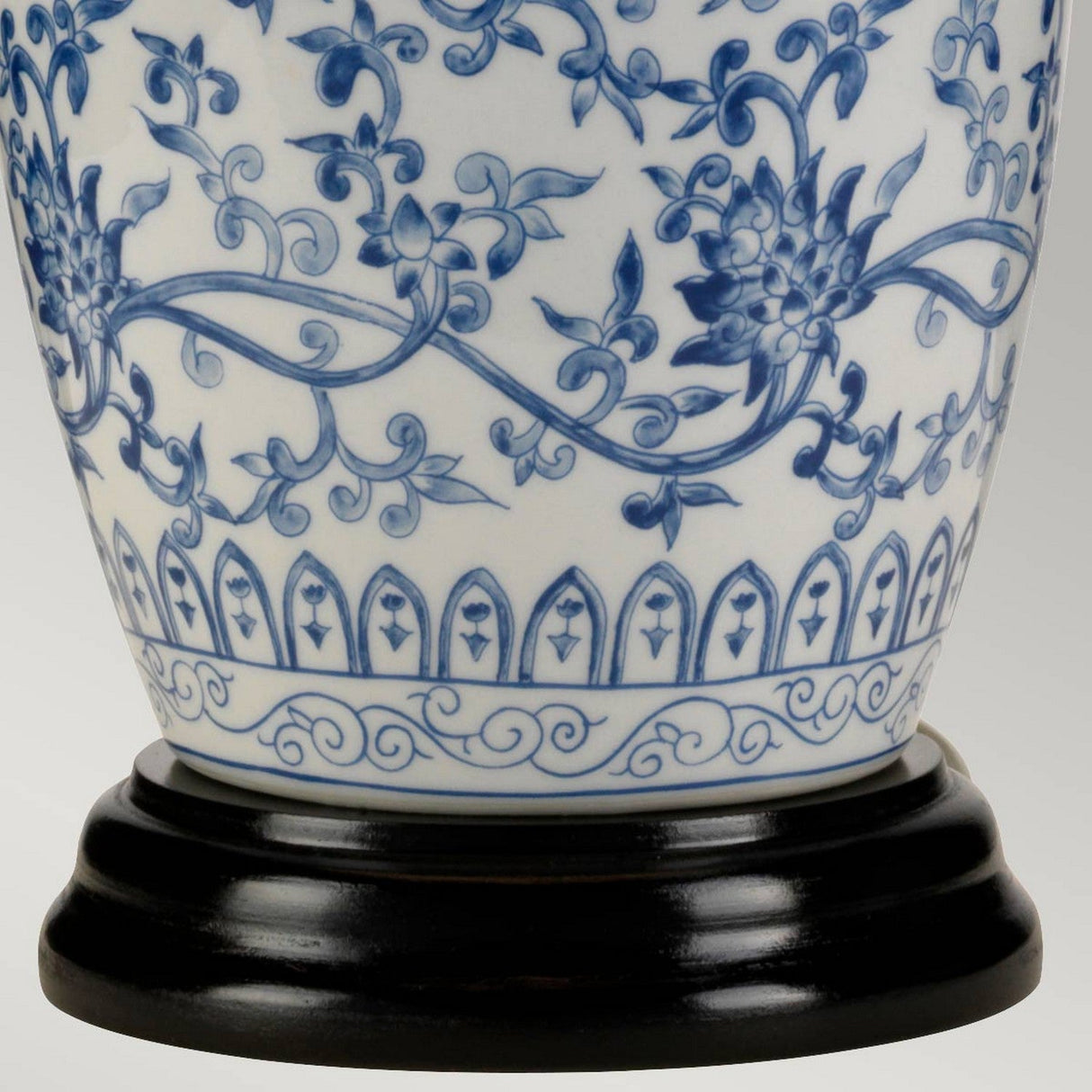 A close-up of the Blue Ginger Jar Table Lamp - Blue & White, reminiscent of classic ceramic vases, showcasing intricate blue floral patterns on a white background and set on a dark wooden base. The design features swirling vines and stylized flowers, highlighting Chinese craftsmanship.