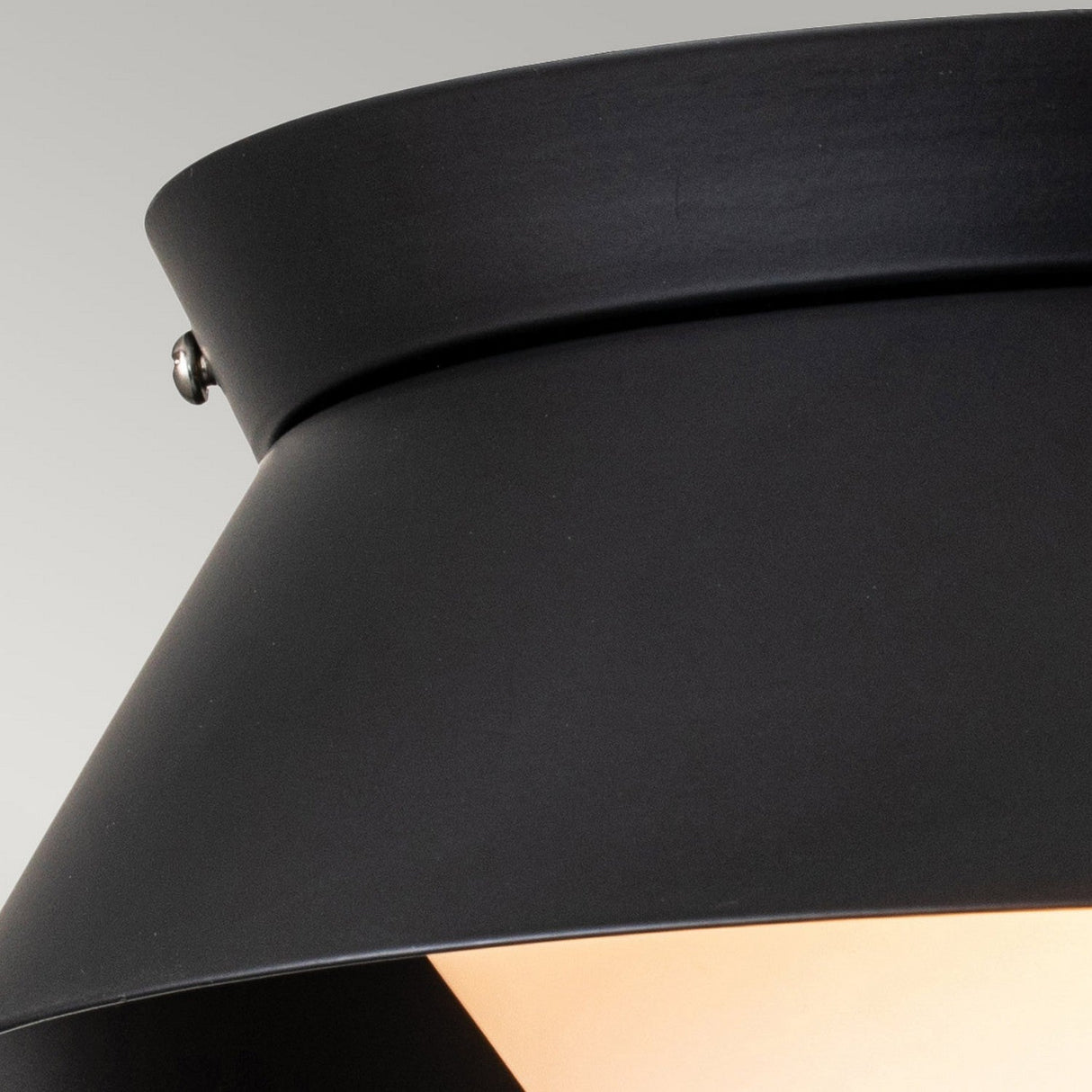 Close-up of the Bowtie 2 Light Flush in matte black metal, showcasing its smooth conical lampshade and luminous interior. This modern fixture offers IP44 rated protection, against a neutral gray background.