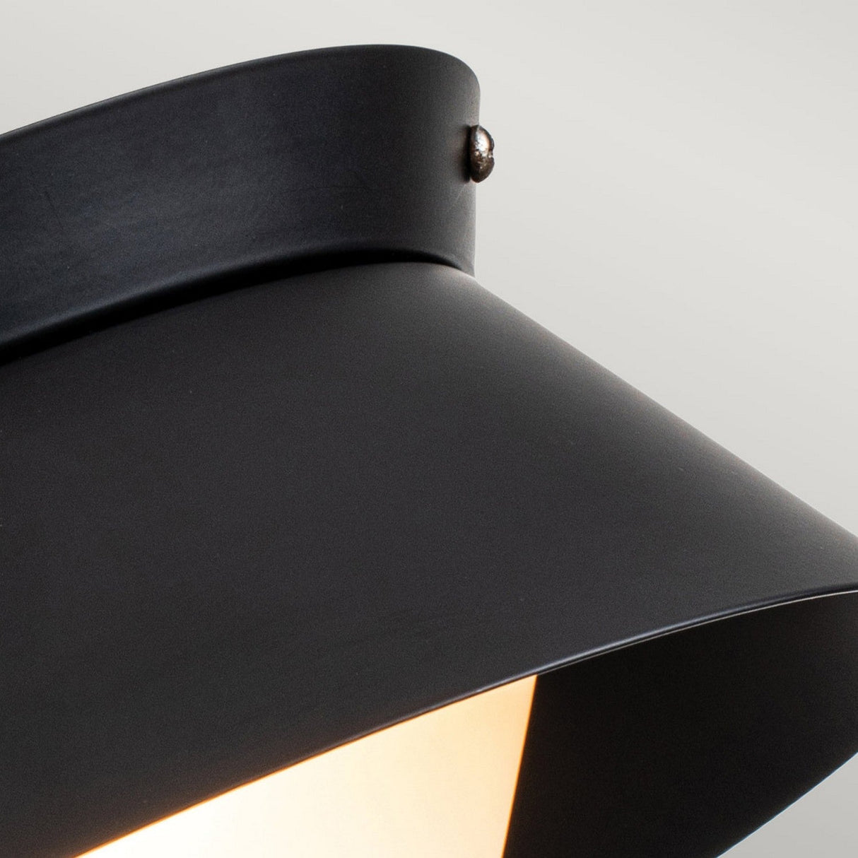 The Bowtie 2 Light Flush in matte black features a smooth, angular design that perfectly highlights its IP44-rated exterior, enhancing the warm glow from within. A small metallic screw at the top edge adds both security and a sleek touch to its functional design.