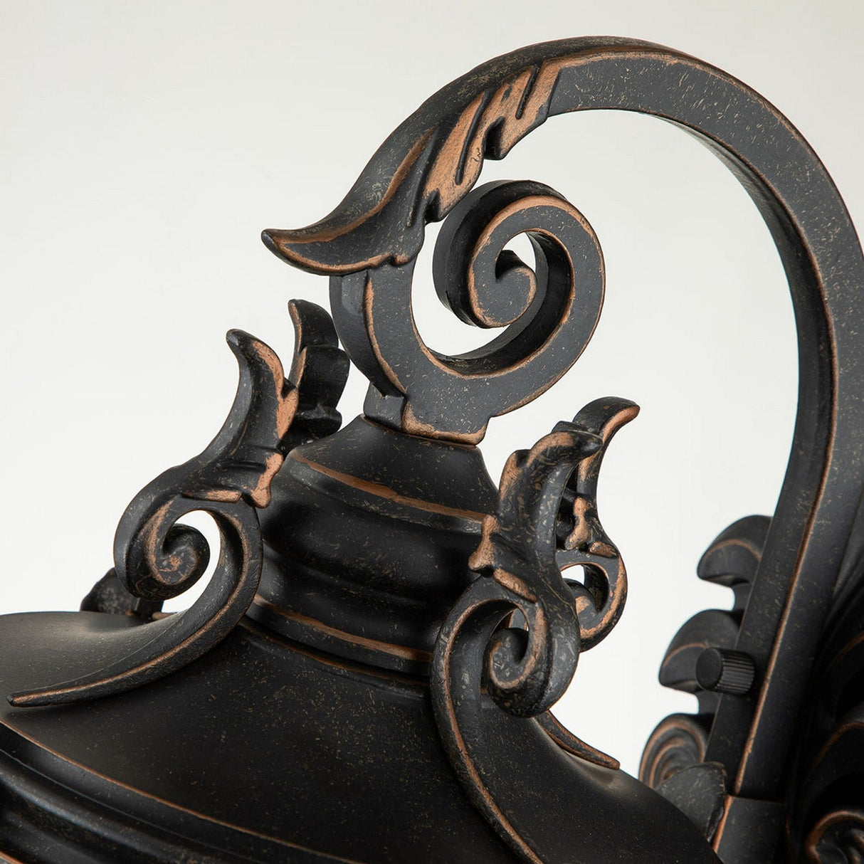 Close-up of the Baltimore 1 Light Outdoor Medium Wall Lantern exhibiting an ornate black metal structure featuring intricate scrollwork and a vintage-inspired design. This piece highlights curved decorative elements and a weathered bronze finish, evoking classic elegance.