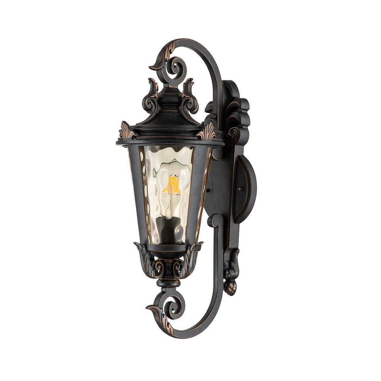 The Baltimore 1 Light Outdoor Medium Wall Lantern - Weathered Bronze features a decorative metal frame with swirling accents. Its vintage-inspired design includes a glass enclosure that showcases a visible bulb, adding an antique charm. This piece effortlessly enhances any space with its rustic allure and elegant craftsmanship.